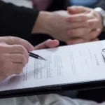 Person filling in a form on a clipboard